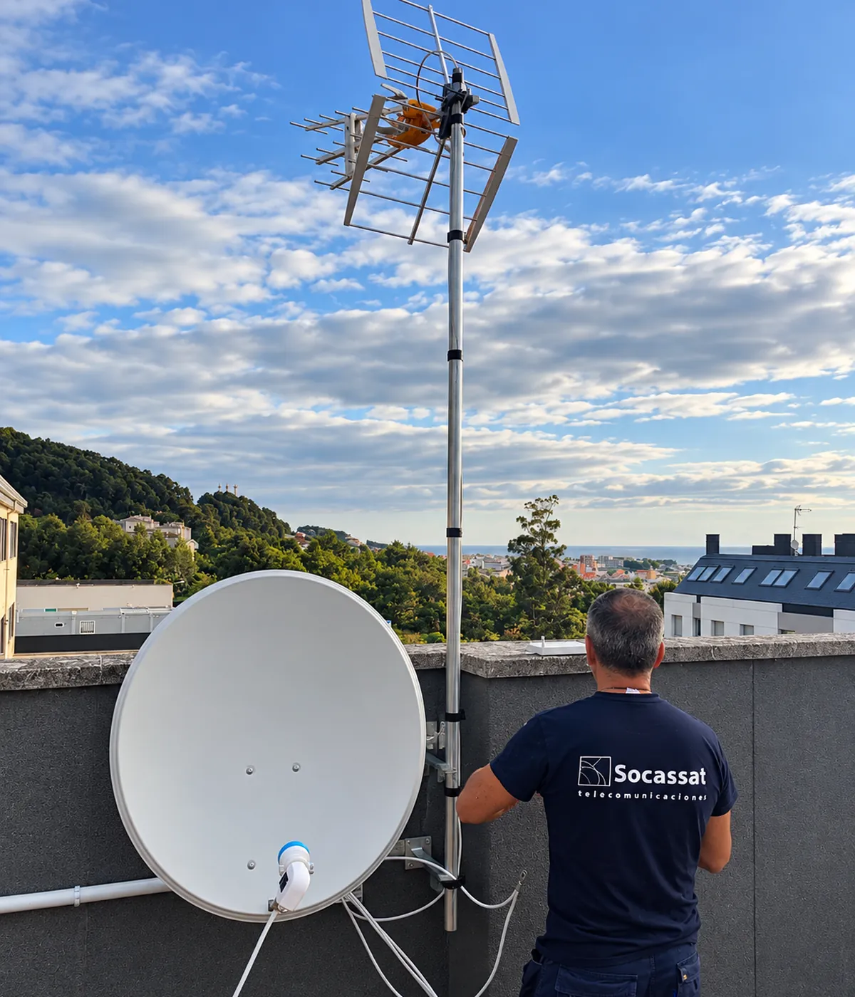 Técnico de Socassat instalando una antena parabólica y un mástil con antenas de TDT en la azotea de un edificio