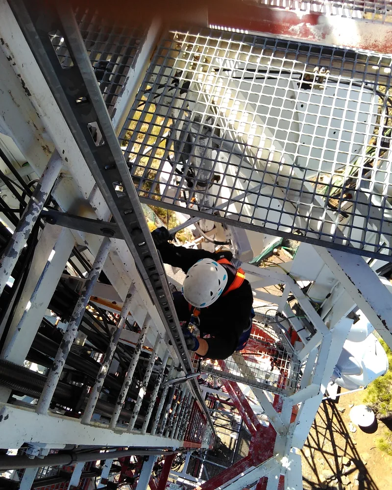 Antenista de Socassat con arnés y casco trabajando en altura en una torre de telecomunicaciones