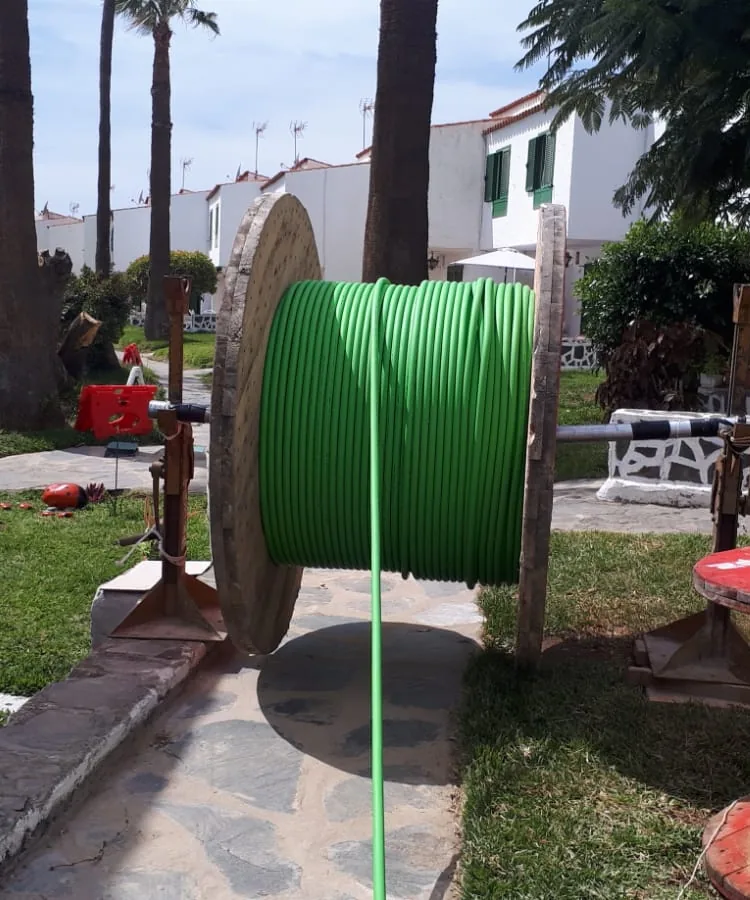 Bobina de cable eléctrico montada sobre gatos para el tendido de una línea subterránea en los jardines de un complejo de apartamentos