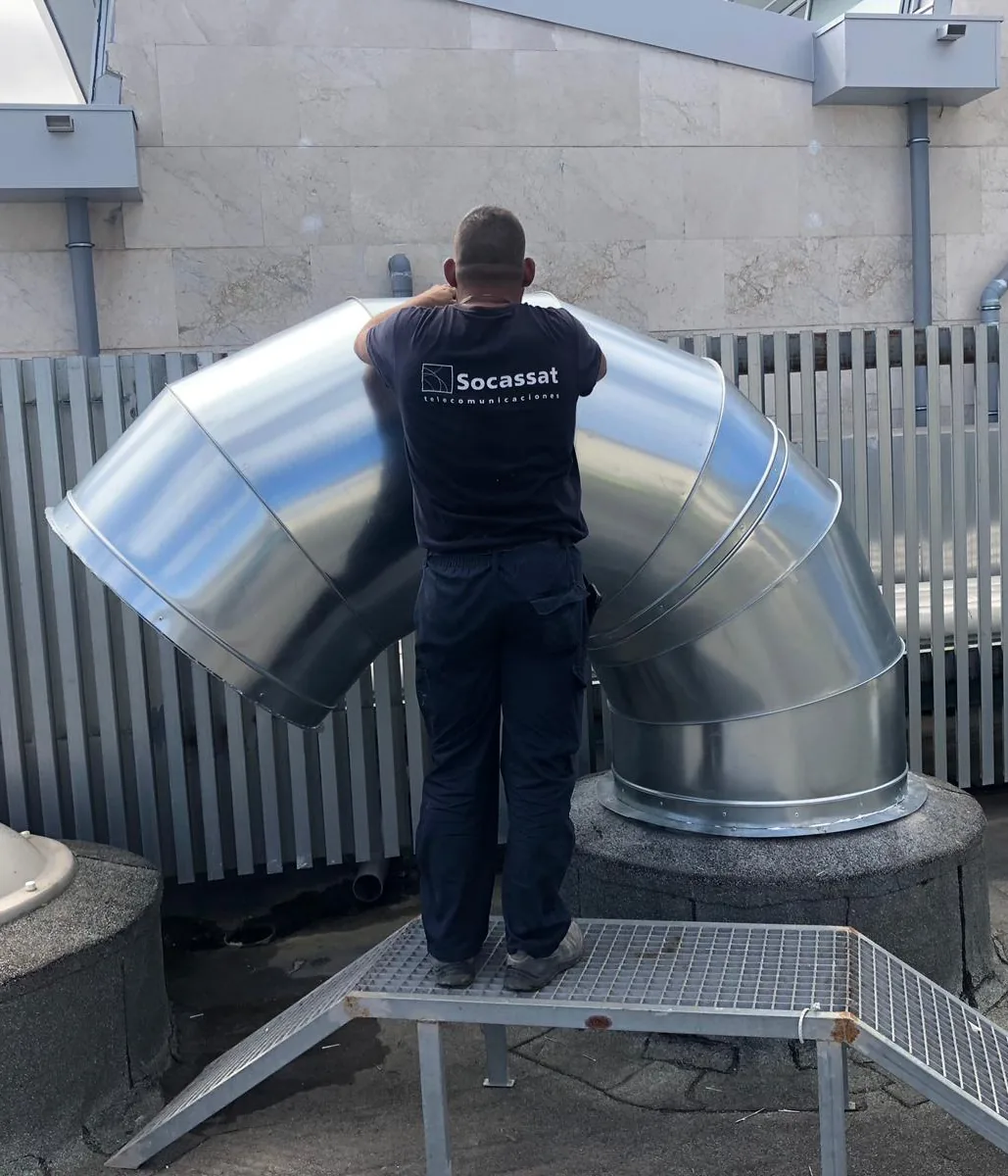 Técnico de Socassat montando un codo de conducto circular de chapa galvanizada en la cubierta de un edificio
