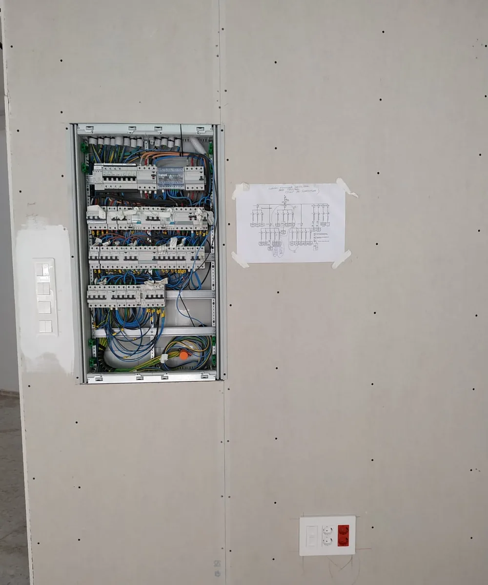 Cuadro eléctrico nuevo empotrado en la pared tras una reforma, con el esquema unifilar de los circuitos junto a él