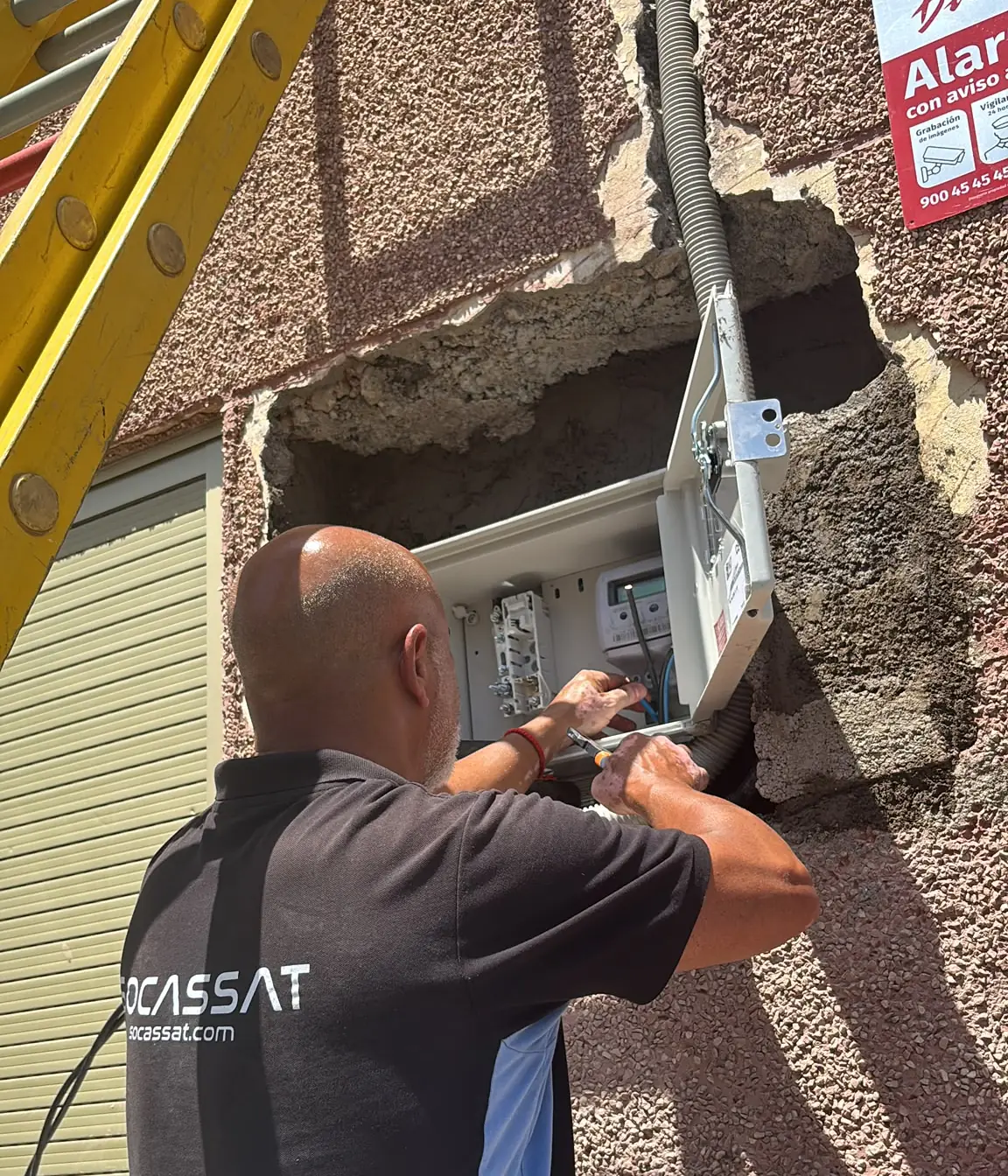 Electricista de Socassat instalando la caja de protección y medida en la fachada de un edificio