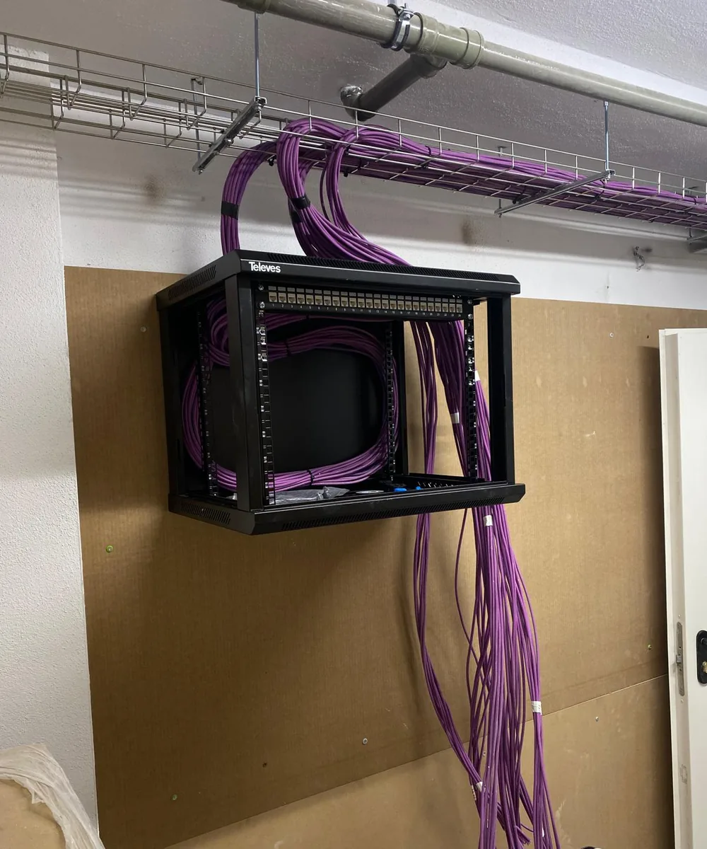 Rack de la ICT en el recinto de telecomunicaciones de un edificio con el cableado de pares trenzados llegando por la bandeja