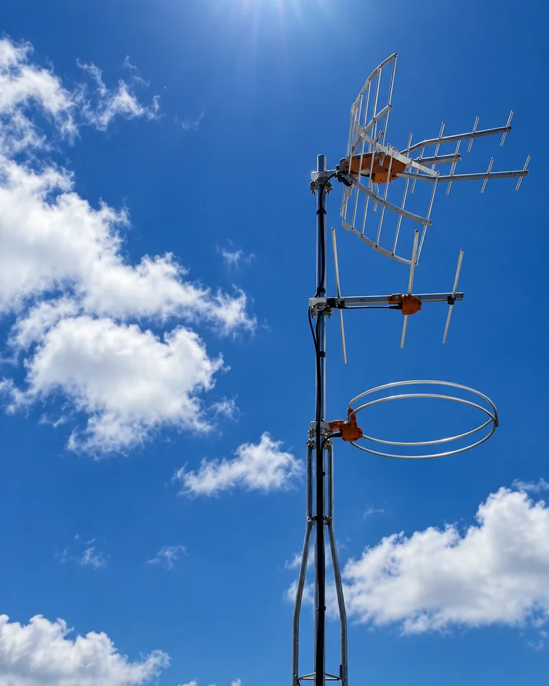 Mástil en la azotea de un edificio con antenas de televisión terrestre y de radio de la ICT