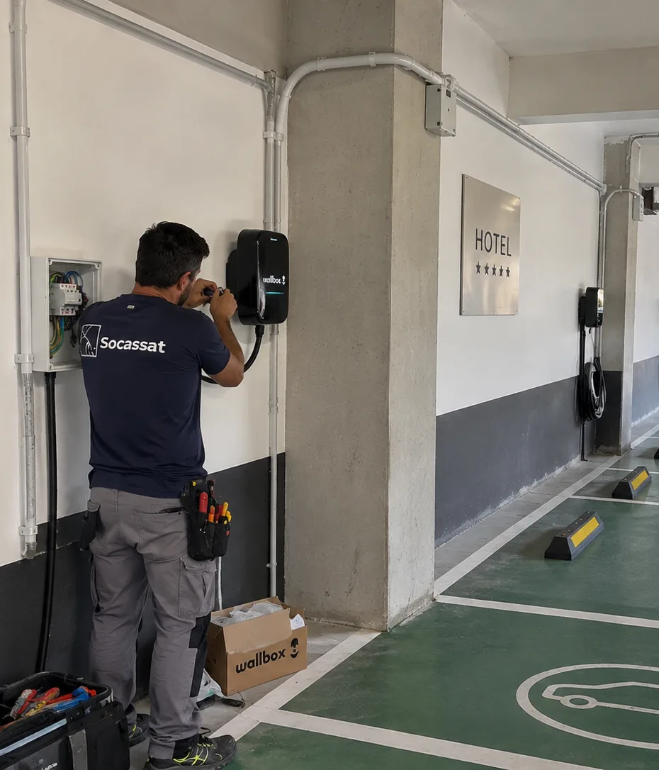 Técnico de Socassat instalando un cargador de coche eléctrico en el aparcamiento de un hotel