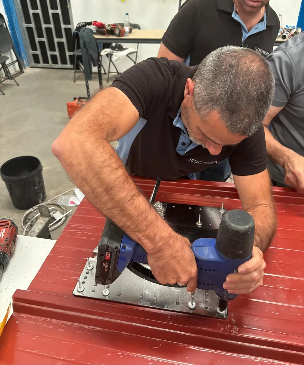 Técnico de Socassat fijando con remachadora la placa de anclaje de una línea de vida en un panel sándwich