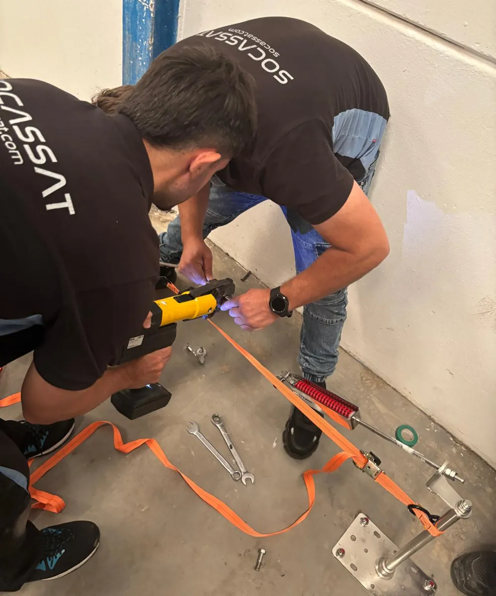 Técnicos de Socassat prensando el terminal del cable de una línea de vida con una prensa de batería