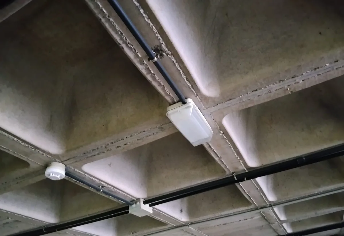Plafón antiguo y canalizaciones eléctricas en el techo de un garaje comunitario antes del cambio a LED
