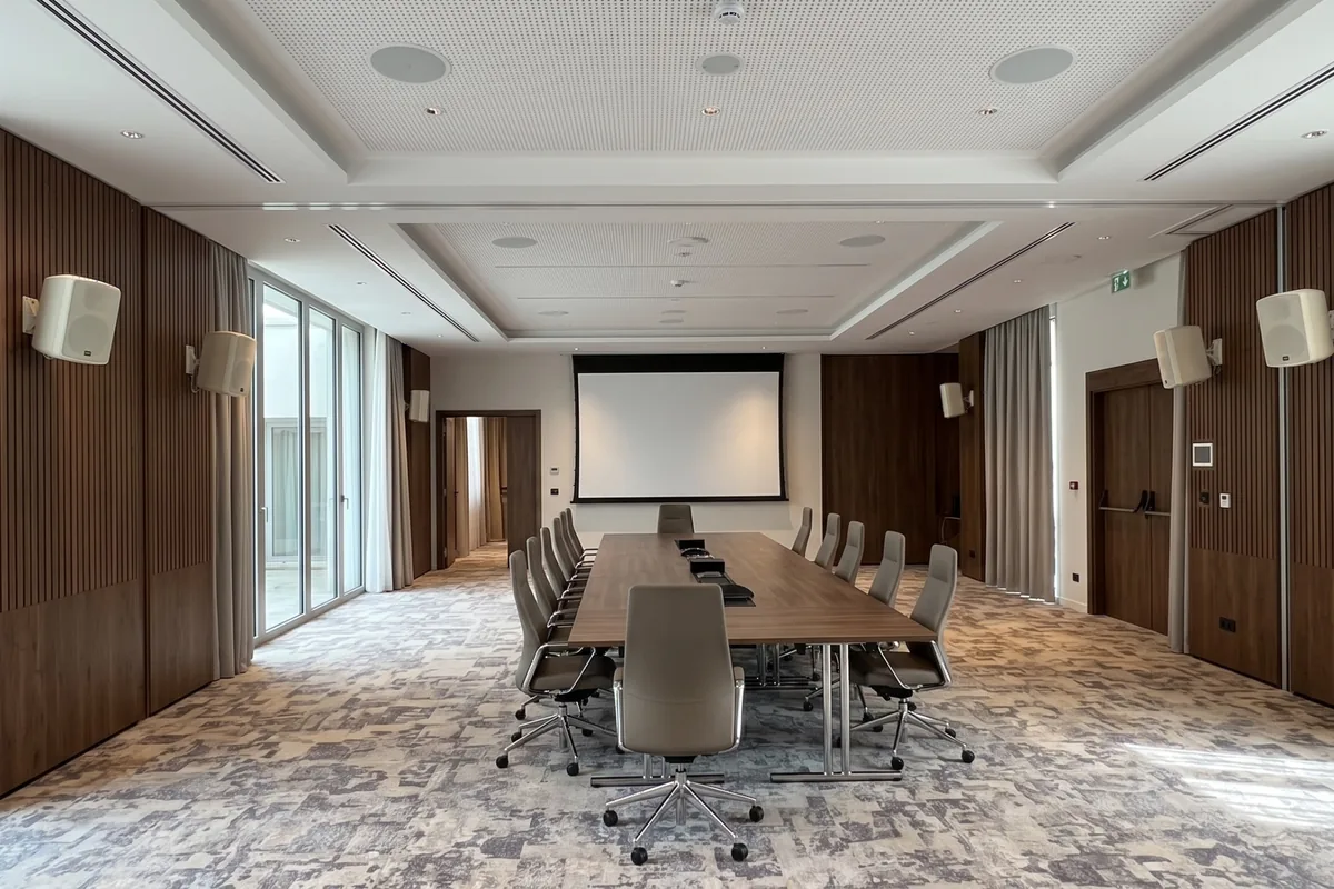 Sala de conferencias de hotel sonorizada con altavoces de pared y de techo y pantalla de proyección