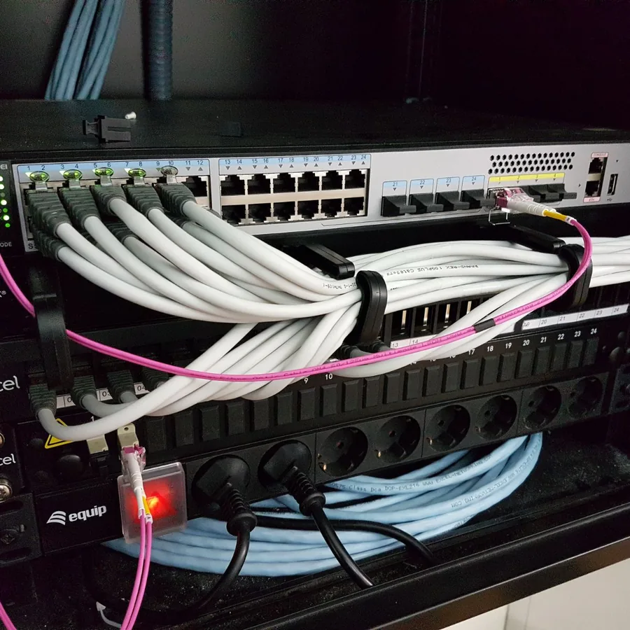 Switch Huawei PoE con latiguillos de cobre ordenados en pasahilos y enlaces de fibra óptica OM4 en un rack