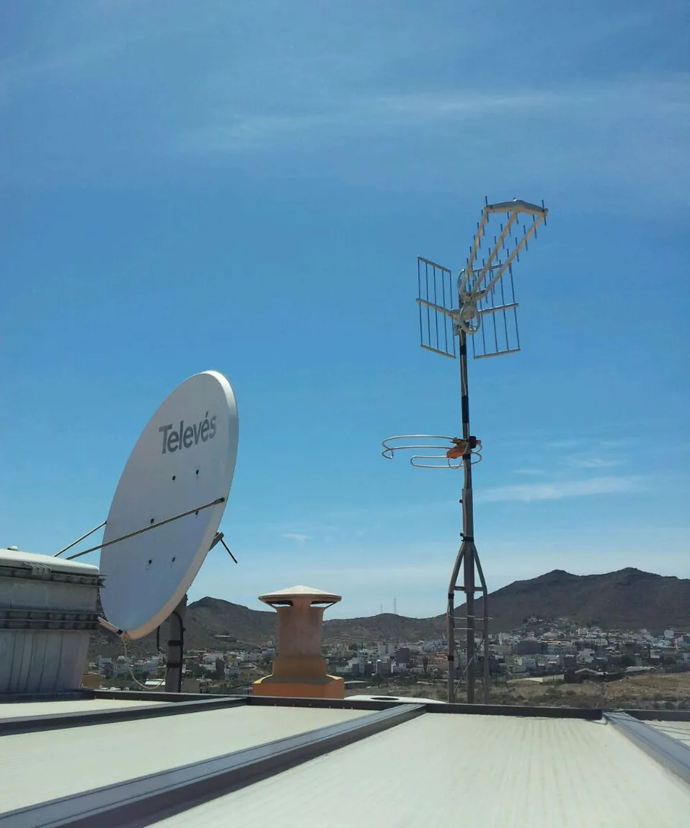 Antena parabólica Televés de gran diámetro y mástil con antenas de TDT en la cubierta de un edificio
