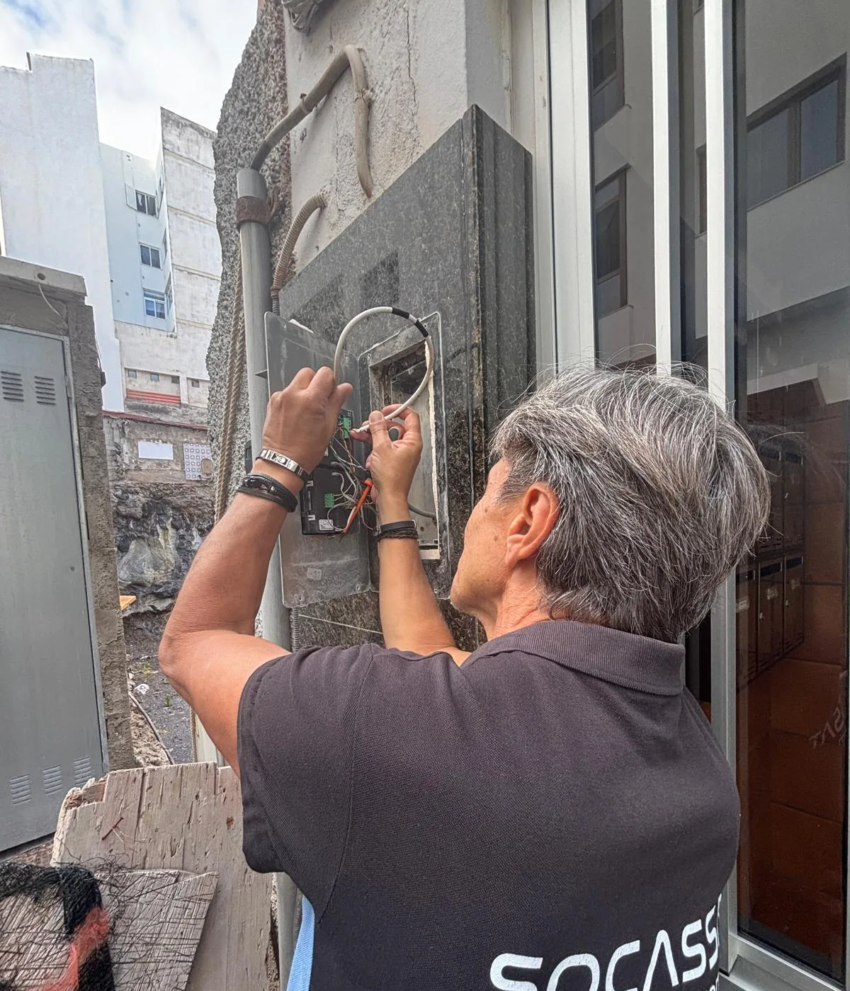 Técnico de Socassat reparando una placa de calle de portero automático con el módulo abierto y el cableado a la vista