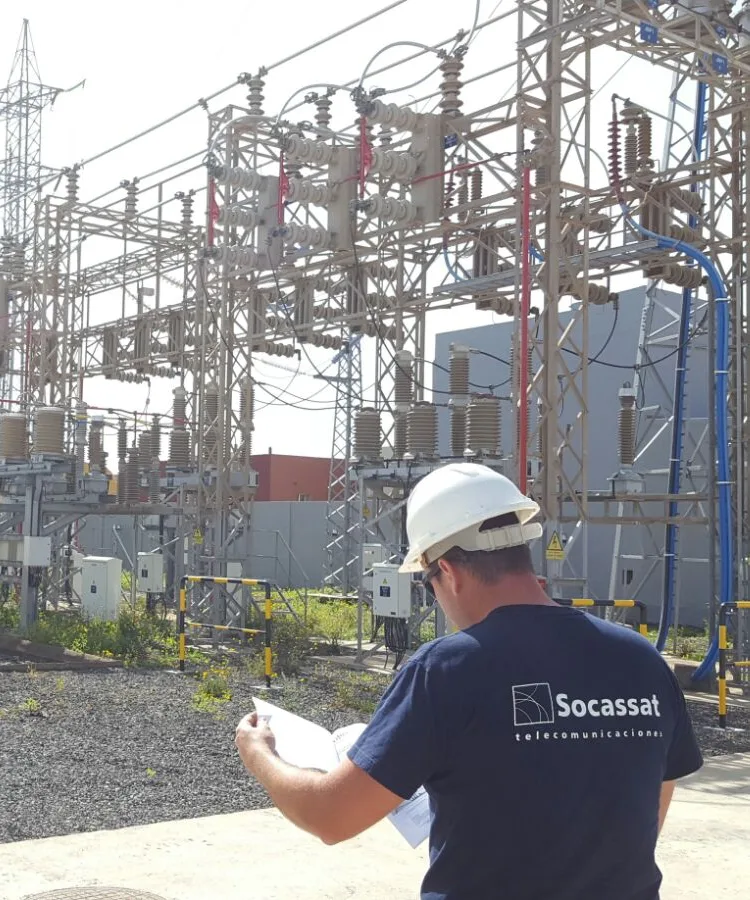 Técnico de Socassat con casco y equipo de protección en una subestación eléctrica de alta tensión