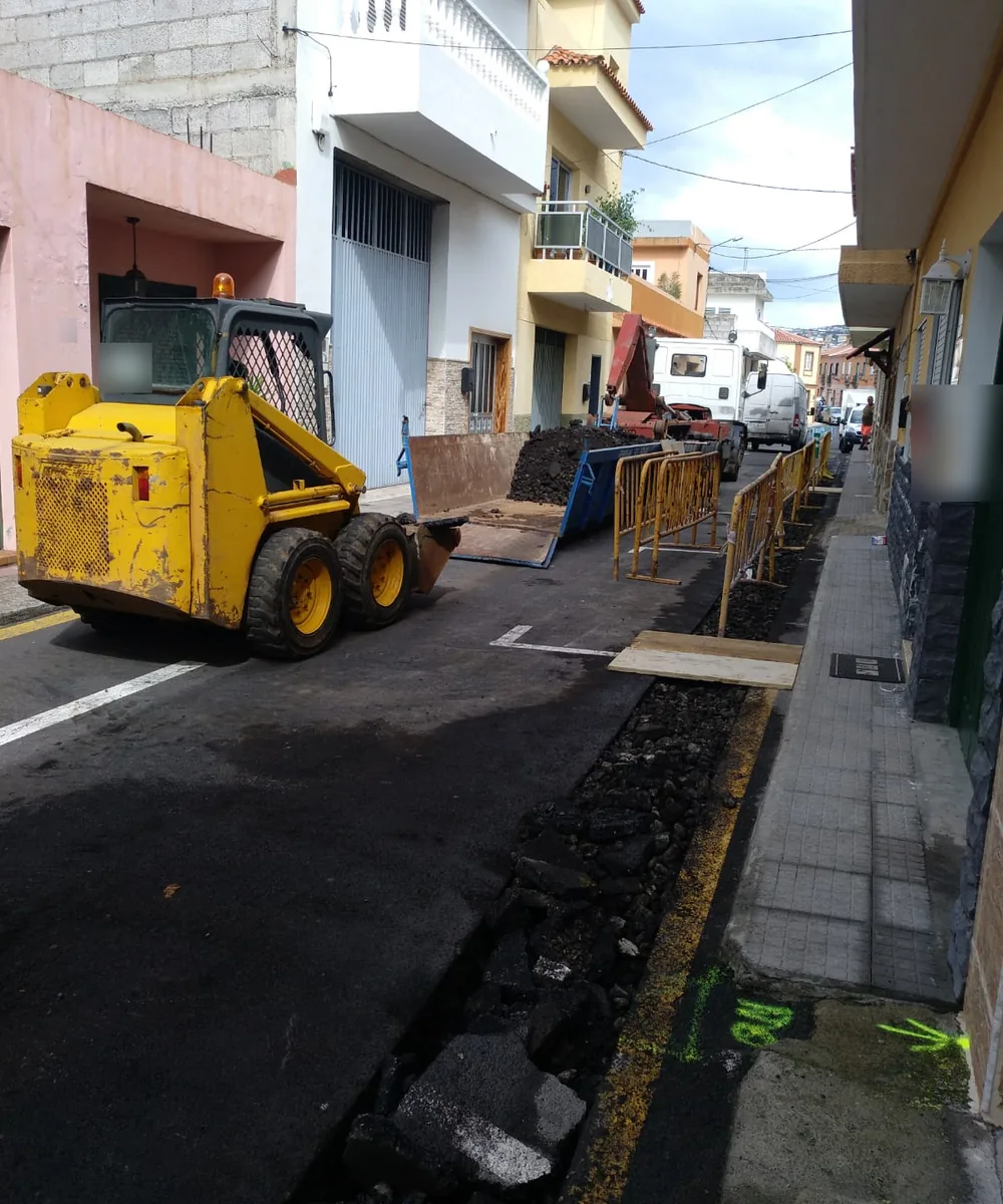 Zanja de una canalización a lo largo de una calle de Tenerife, con el vallado de la obra y la maquinaria